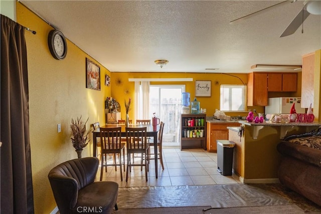 dining room featuring ceiling fan, a textured ceiling, and light tile patterned floors