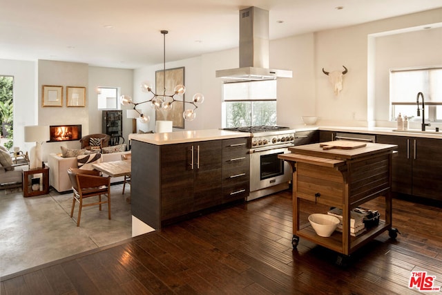 kitchen with high end stainless steel range oven, island range hood, sink, and dark brown cabinets