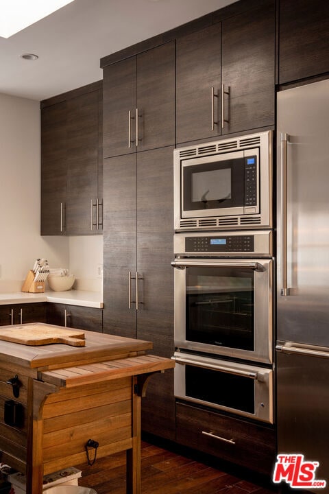 kitchen featuring dark hardwood / wood-style flooring, dark brown cabinets, and stainless steel appliances