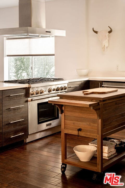 kitchen with stainless steel range, wall chimney exhaust hood, and dark hardwood / wood-style floors