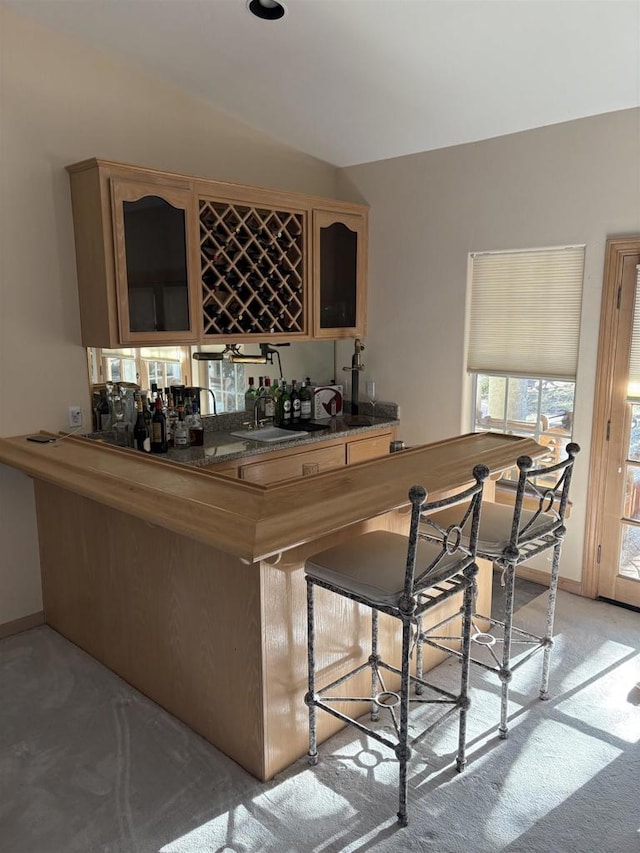 bar with sink, light carpet, and lofted ceiling