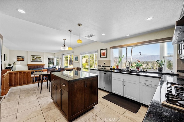 kitchen featuring sink, decorative light fixtures, a center island, stainless steel dishwasher, and a mountain view