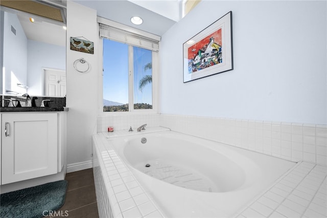 bathroom featuring tile patterned flooring, vanity, and a relaxing tiled tub