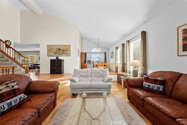 living room featuring a notable chandelier, high vaulted ceiling, and light wood-type flooring