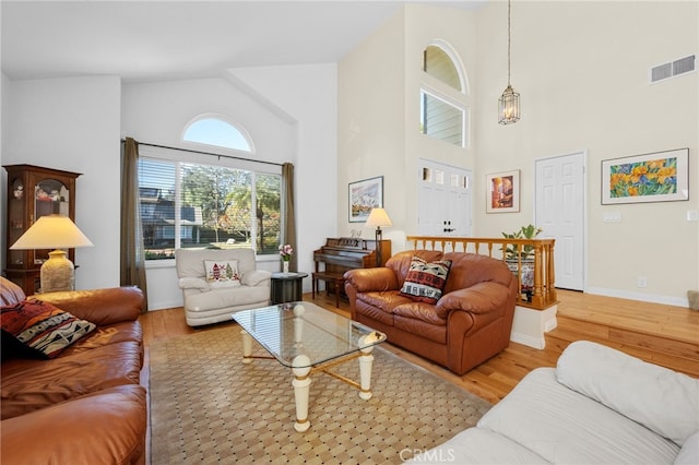 living room featuring high vaulted ceiling and light hardwood / wood-style flooring