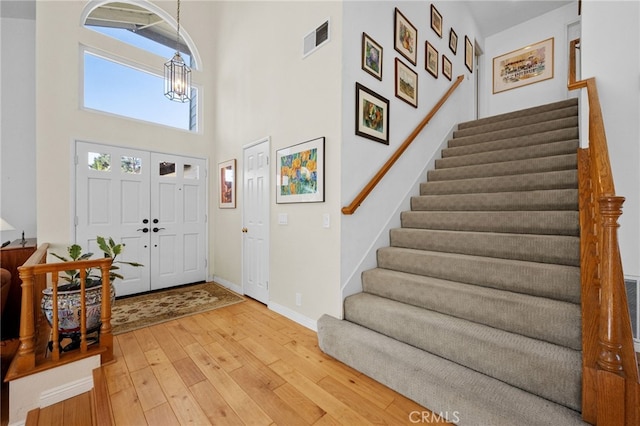 foyer entrance featuring hardwood / wood-style flooring, a high ceiling, and a notable chandelier