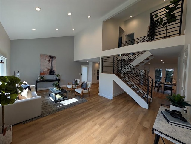 living room with high vaulted ceiling, french doors, and light hardwood / wood-style floors