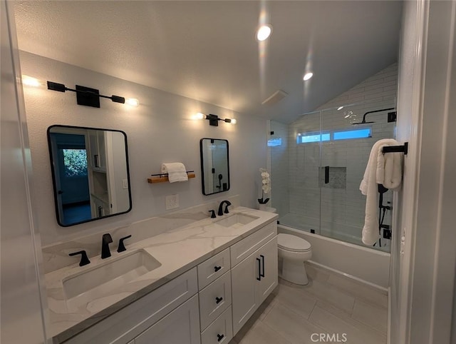 full bathroom with lofted ceiling, vanity, tile patterned flooring, toilet, and shower / bath combination with glass door