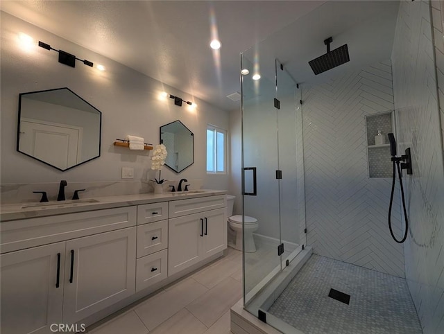 bathroom featuring toilet, vanity, tile patterned floors, and a shower with door