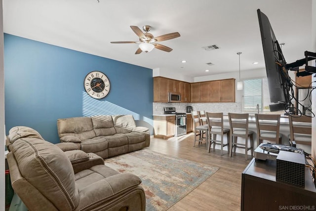 living room with ceiling fan and light hardwood / wood-style floors