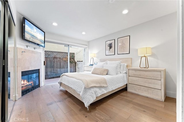 bedroom with wood-type flooring, access to exterior, and a fireplace