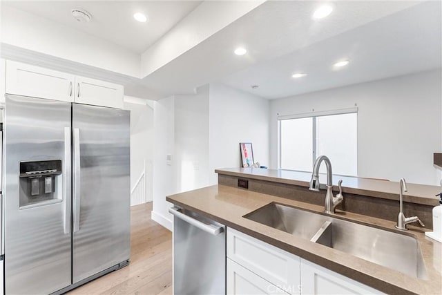 kitchen with sink, white cabinetry, appliances with stainless steel finishes, and light hardwood / wood-style flooring