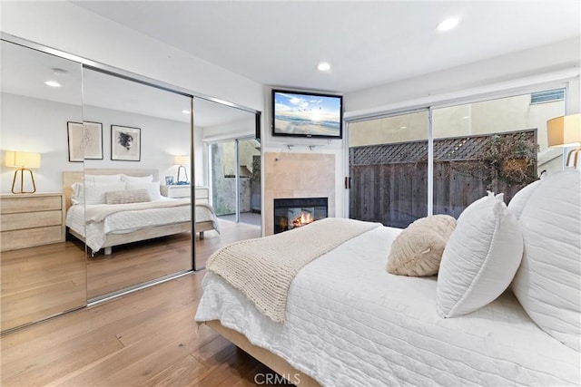 bedroom with a tiled fireplace and hardwood / wood-style flooring