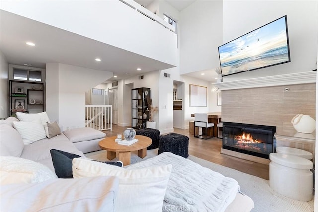 living room featuring light hardwood / wood-style flooring, a towering ceiling, and a fireplace