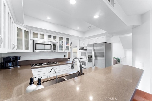 kitchen featuring kitchen peninsula, white cabinets, sink, and appliances with stainless steel finishes