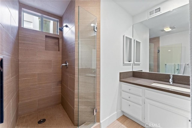 bathroom with a shower with door and vanity