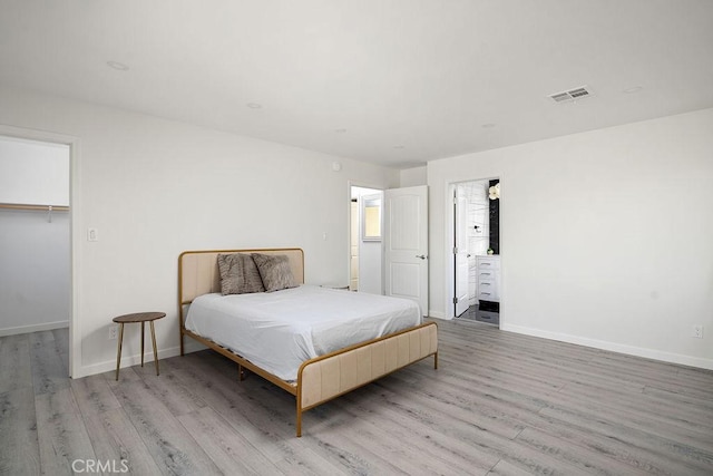 bedroom featuring a closet, a walk in closet, and light hardwood / wood-style flooring