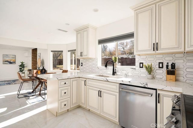 kitchen with stainless steel dishwasher, cream cabinetry, sink, and kitchen peninsula