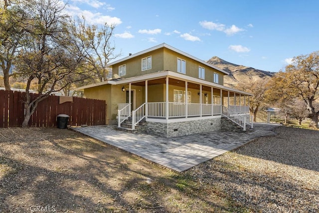 rear view of property with a porch, a mountain view, and a patio