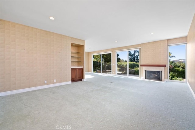 unfurnished living room with light colored carpet and built in shelves