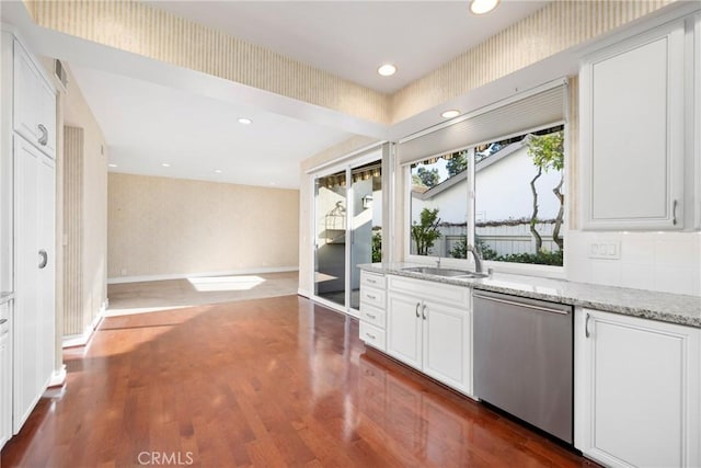 kitchen featuring light stone countertops, sink, white cabinetry, and stainless steel dishwasher