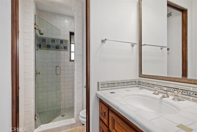 bathroom with toilet, vanity, tile patterned flooring, tasteful backsplash, and a shower with shower door