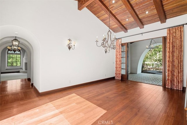 empty room with wooden ceiling, lofted ceiling with beams, a chandelier, and hardwood / wood-style flooring