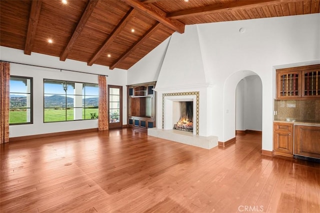 unfurnished living room featuring high vaulted ceiling, beam ceiling, a fireplace, and wooden ceiling