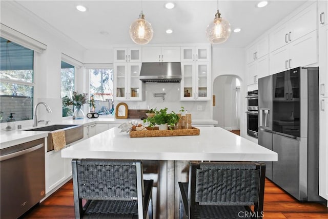 kitchen with white cabinetry, stainless steel appliances, a kitchen breakfast bar, hanging light fixtures, and a kitchen island