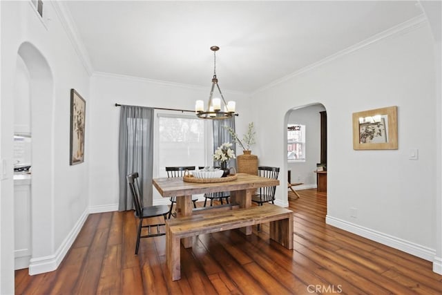 dining room with dark wood-type flooring, crown molding, and a notable chandelier