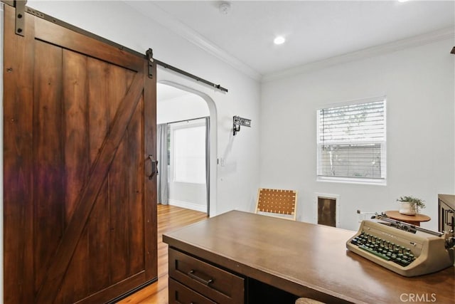 office area with ornamental molding, a barn door, and light wood-type flooring