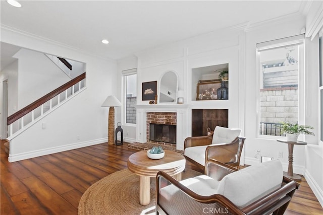 living room featuring wood-type flooring, a fireplace, and crown molding