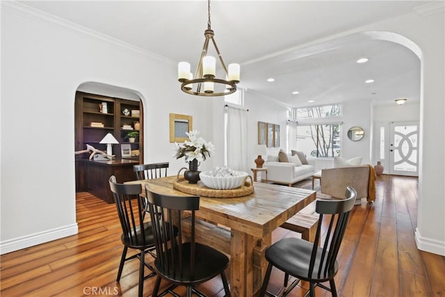 dining room with dark hardwood / wood-style flooring, ornamental molding, and an inviting chandelier