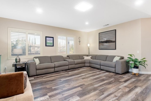 living area featuring baseboards, visible vents, and wood finished floors