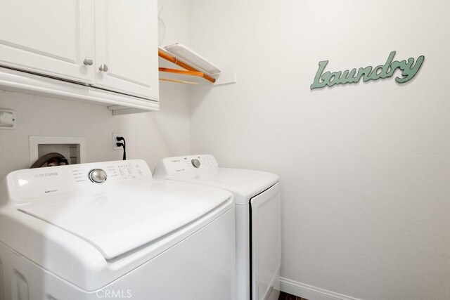 clothes washing area with cabinets and independent washer and dryer