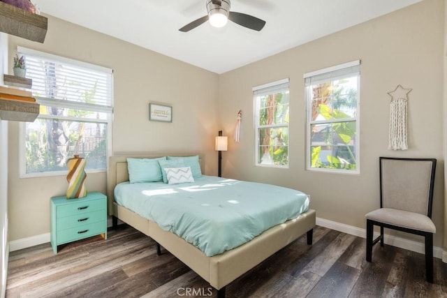 bedroom with multiple windows, wood finished floors, and baseboards