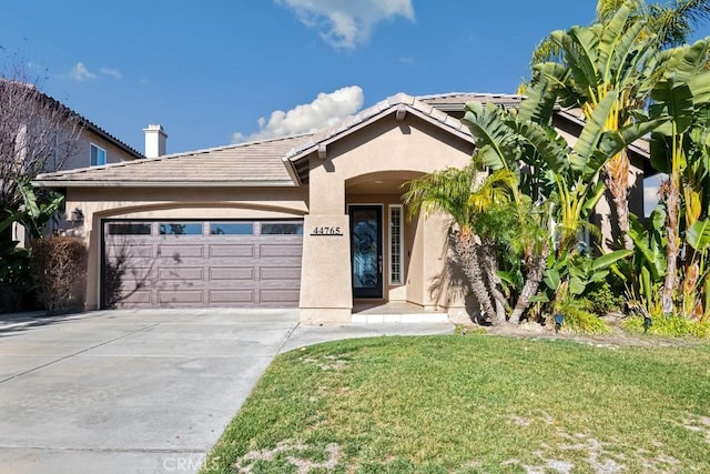 view of front of house with concrete driveway, a tiled roof, an attached garage, a front lawn, and stucco siding