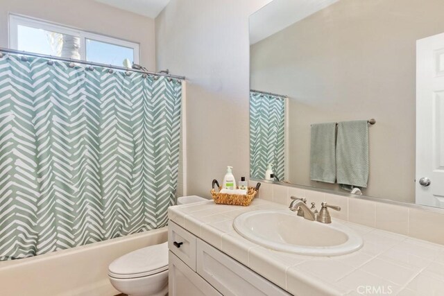 full bathroom featuring toilet, vanity, and shower / bathtub combination with curtain