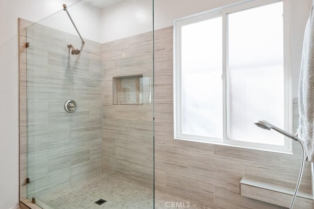 full bath featuring a tile shower and a wealth of natural light