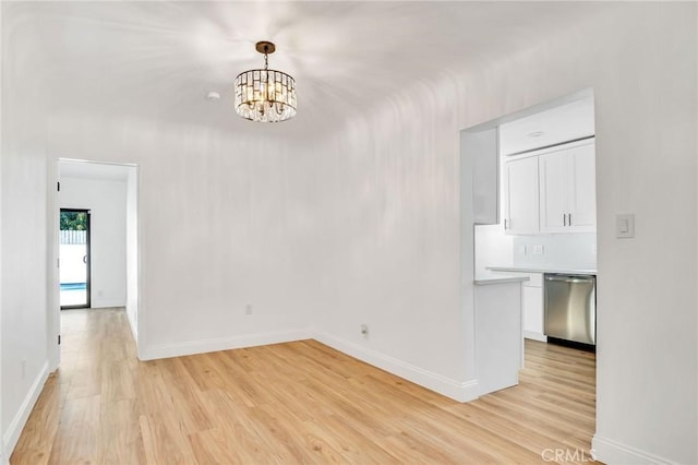 spare room with a chandelier and light hardwood / wood-style floors