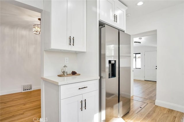 bar featuring stainless steel fridge, white cabinetry, and light hardwood / wood-style floors