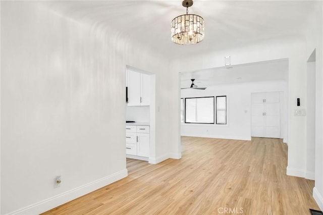 interior space featuring ceiling fan with notable chandelier and light hardwood / wood-style flooring