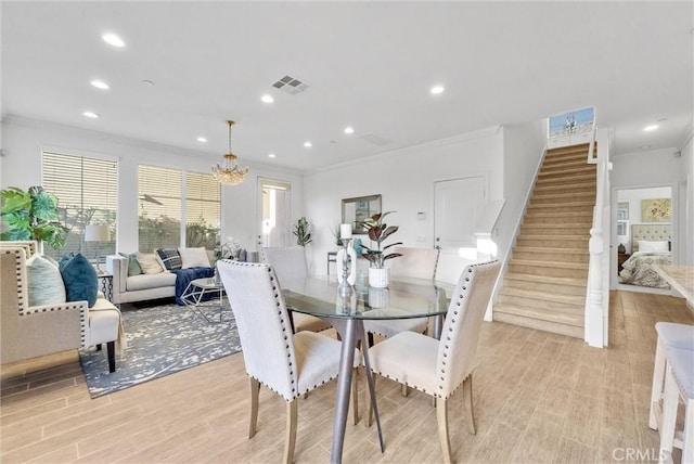 dining space featuring light wood-type flooring, an inviting chandelier, and crown molding