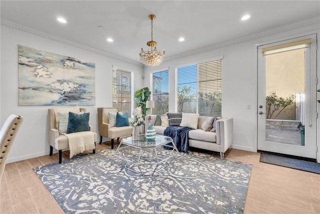 living area with a notable chandelier, ornamental molding, and hardwood / wood-style floors