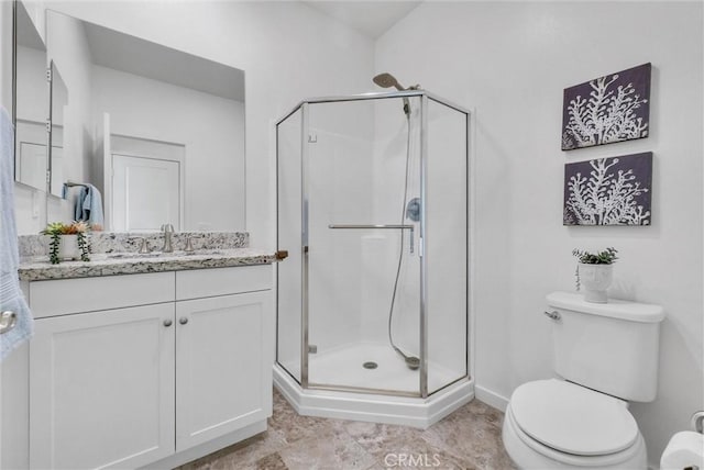 bathroom featuring toilet, vanity, and a shower with door