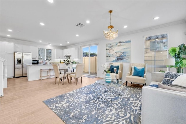 living room featuring a notable chandelier, crown molding, and light hardwood / wood-style flooring