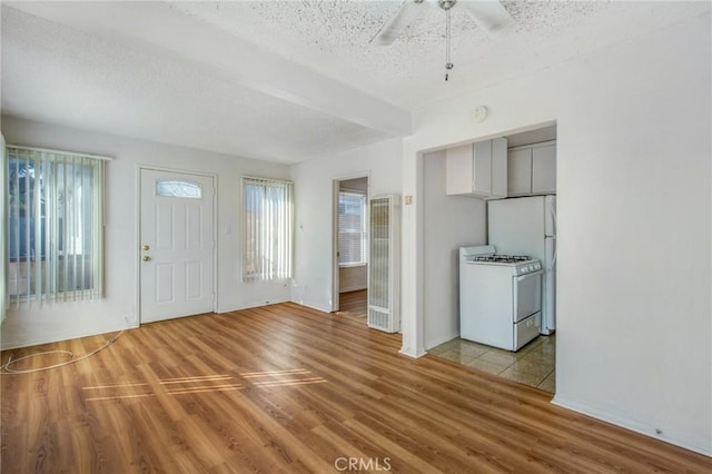 foyer featuring light wood-type flooring, ceiling fan, and a textured ceiling