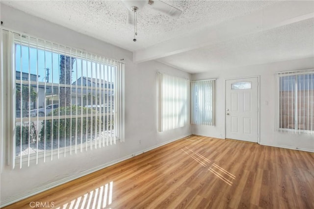 entrance foyer featuring ceiling fan, hardwood / wood-style floors, beam ceiling, and a textured ceiling