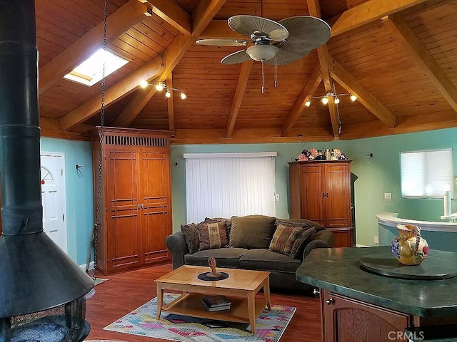 living room featuring dark hardwood / wood-style flooring, a wood stove, ceiling fan, wooden ceiling, and lofted ceiling with skylight