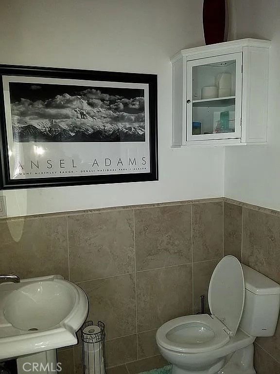 bathroom with sink, tile walls, and toilet